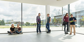 Studierende im Gespräch vor einem Fenster